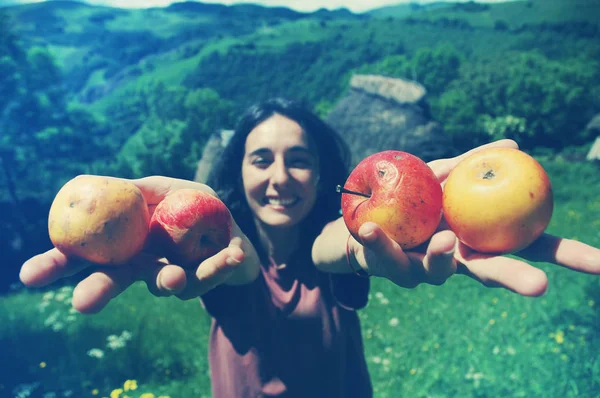 Amistosa mujer sonriente sosteniendo manzanas en sus manos —  Fotos de Stock