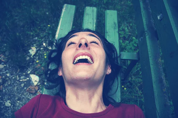 Mujer cosquillas riendo en un banco — Foto de Stock