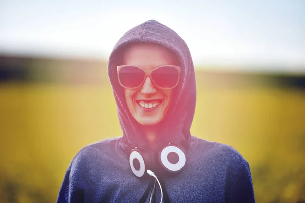 Ragazza hipster con cappuccio, occhiali da sole e cuffie all'aperto — Foto Stock