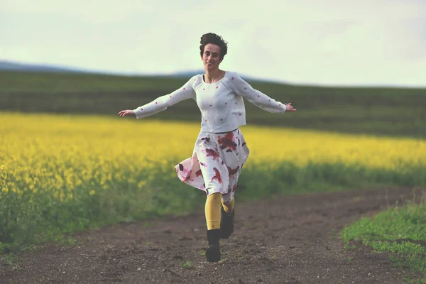 Счастливая девушка бежит по сельской дороге — стоковое фото
