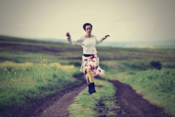 Vintage mulher correndo em uma estrada rural — Fotografia de Stock