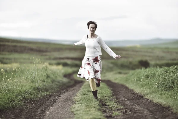 Happy girl courir sur une route de campagne — Photo