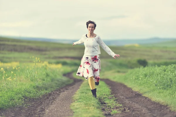Chica feliz corriendo en un camino rural — Foto de Stock