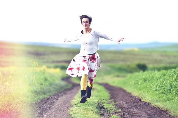 Mujer positiva corriendo en una carretera rural — Foto de Stock