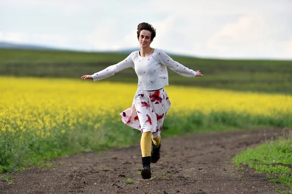 Улыбающаяся женщина бежит по проселочной дороге — стоковое фото