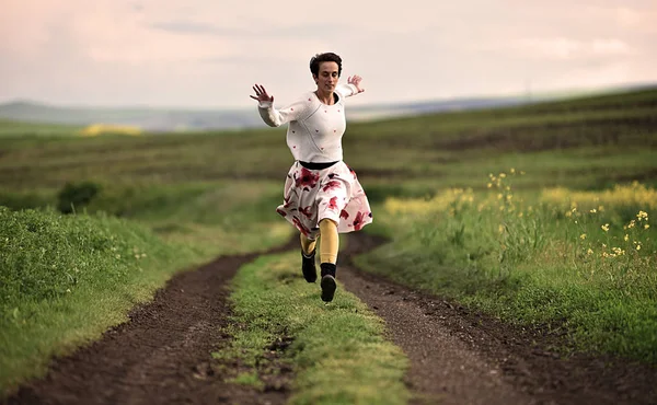 Jovencita alegre corriendo por un camino rural —  Fotos de Stock