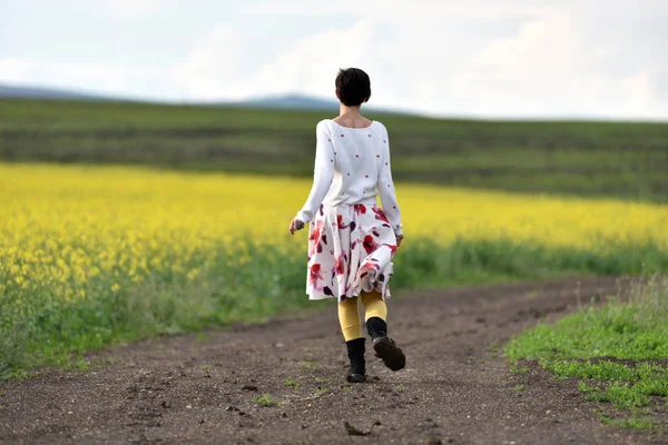 Gioiosa donna positiva che corre su una strada di campagna — Foto Stock