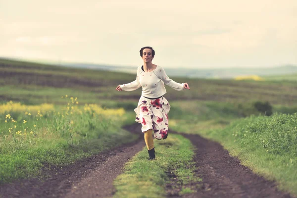 在乡村路奔跑的白色裙子的妇女 — 图库照片