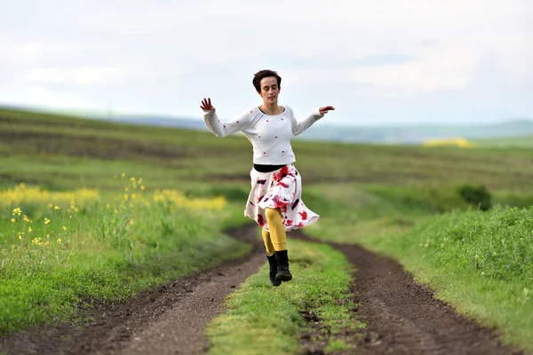 Jovem mulher positiva correndo em uma estrada rural — Fotografia de Stock