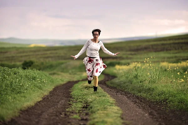 Radostné žena běží na venkovské cestě — Stock fotografie