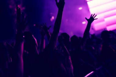 Yükseltilmiş silah ile bir konser sırasında sallanan kalabalık.