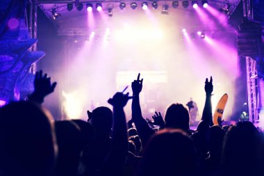 Yükseltilmiş silah ile bir konser sırasında sallanan kalabalık.