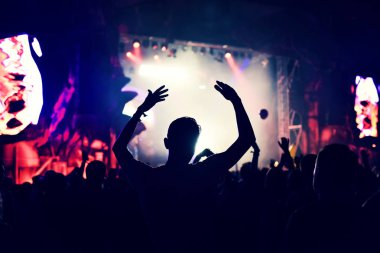 Yükseltilmiş silah ile bir konser sırasında sallanan kalabalık.