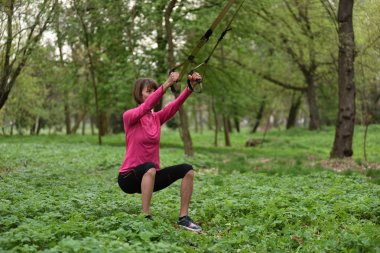 Süspansiyon antrenörle trx egzersiz yaparak güzel genç kadın