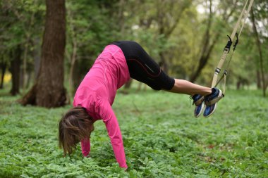 Süspansiyon antrenörle trx egzersiz yaparak güzel genç kadın