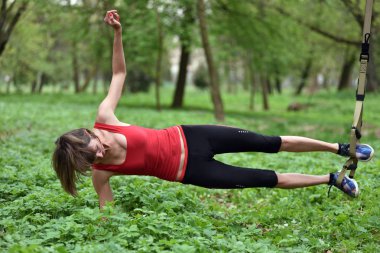 Süspansiyon antrenörle trx egzersiz yaparak güzel genç kadın