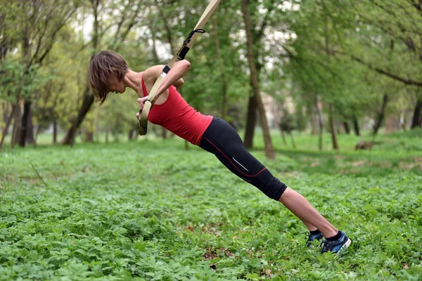 Ung kvinna gör suspension training med fitness remmar i den — Stockfoto