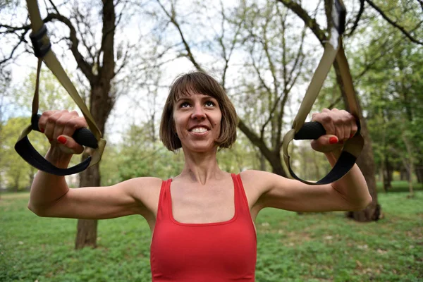 Woman doing arms biceps curl training with trx fitness straps — Stock Photo, Image