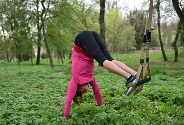 Красивая молодая женщина делает TRX упражнения с тренером подвески — стоковое фото