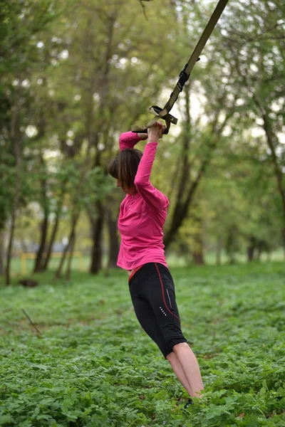 Молодая привлекательная женщина занимается растяжкой тела с помощью трх-фитнес — стоковое фото