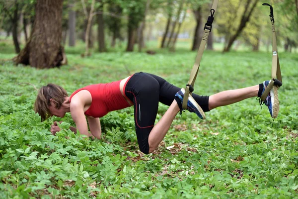 Hermosa joven haciendo ejercicio TRX con entrenador de suspensión — Foto de Stock