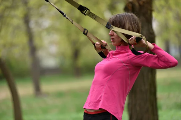 Mujer haciendo brazos bíceps curl entrenamiento con correas de fitness trx — Foto de Stock