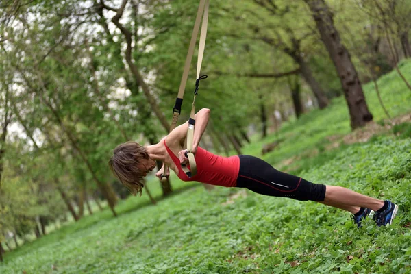 Ung kvinna gör suspension training med fitness remmar i den — Stockfoto