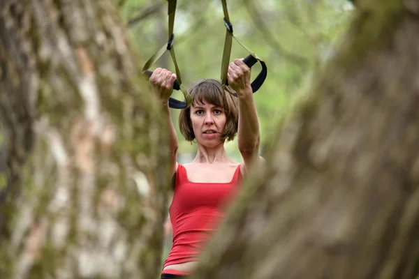 Kobieta robi broni, którą biceps curl szkolenie trx fitness paski — Zdjęcie stockowe