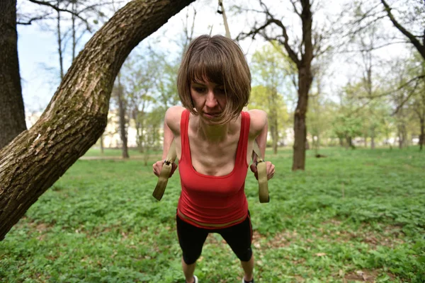 Junge Frau macht Aufhängungstraining mit Fitnessgurten in der — Stockfoto