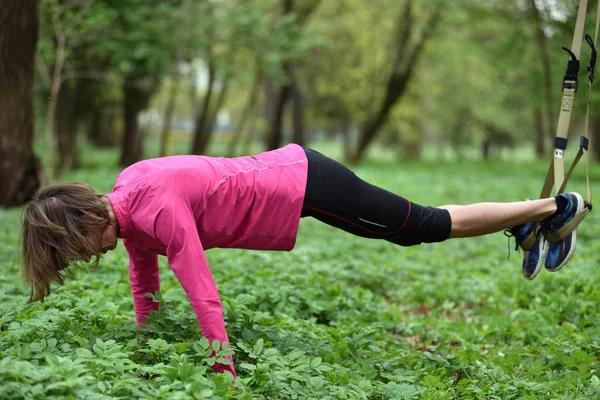 Hermosa joven haciendo ejercicio TRX con entrenador de suspensión — Foto de Stock