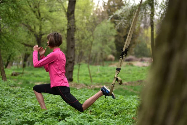 Hermosa joven haciendo ejercicio TRX con entrenador de suspensión — Foto de Stock