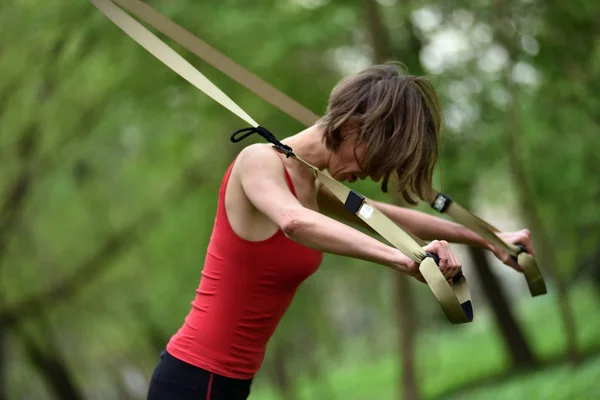 Jovem mulher faz treinamento de suspensão com tiras de fitness no — Fotografia de Stock