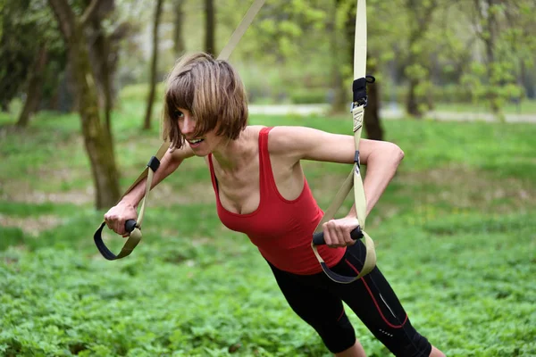 Ung kvinna gör suspension training med fitness remmar i den — Stockfoto