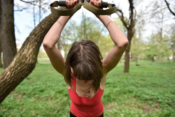 Молодая привлекательная женщина занимается растяжкой тела с помощью трх-фитнес — стоковое фото