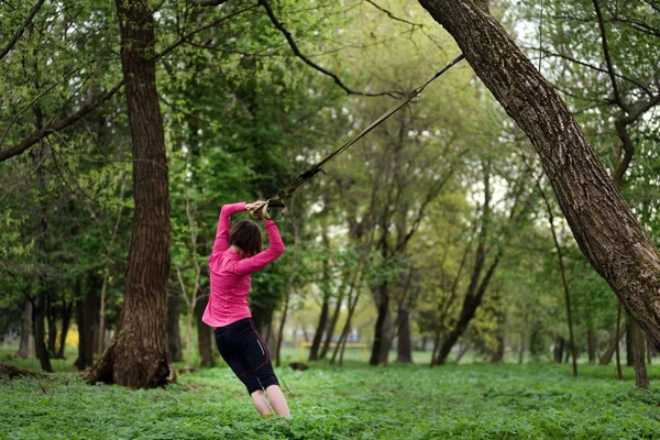 Giovane donna attraente fa body stretching con trx fitness str — Foto Stock