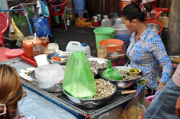 Donna che vende cibo di strada, lumache di mare e altri frutti di mare con ve — Foto Stock