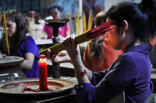 Asian people praying and burning incense sticks in a pagoda — Stock Photo, Image