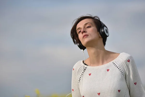 Mooie Kaukasische meisje luisteren naar muziek met hoofdtelefoon in th — Stockfoto