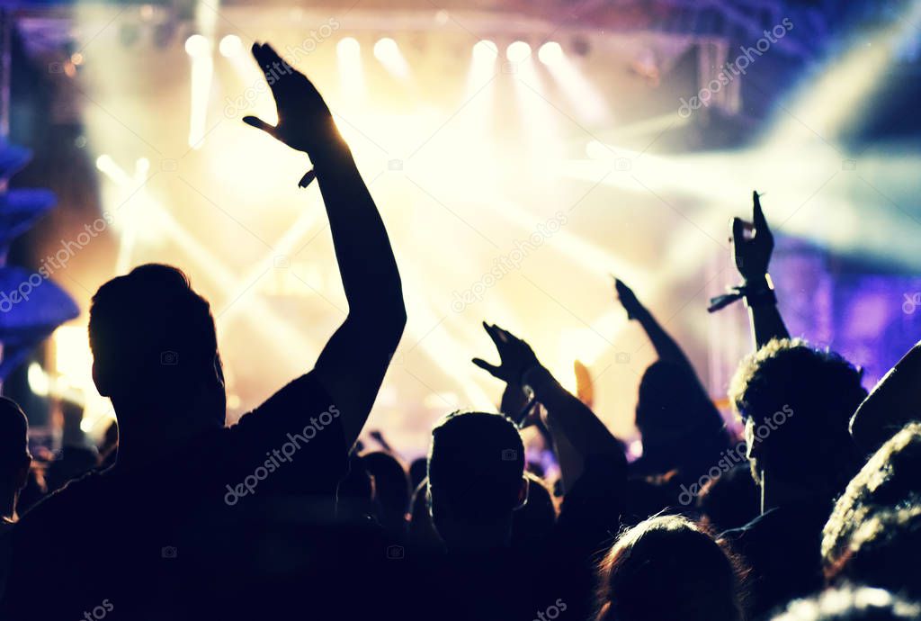 Crowd at a music concert, audience raising hands up