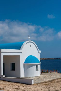 Sahilde mavi çatılı geleneksel Beyaz Şapel. Agioi 