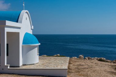 Sahilde mavi çatılı geleneksel Beyaz Şapel. Agioi 