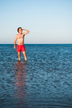 İnce adam deniz suyu kırmızı mayo poz