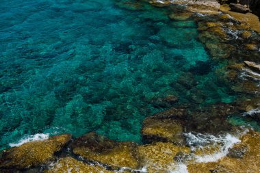 Kristal berrak turkuaz deniz suyu arka planı ve kayalık sahil