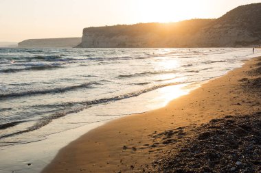 Dalgalar sahil kumu günbatımı sırasında yaklaşıyor