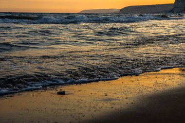 Günbatımı sırasında kumsala yaklaşırken dalgalar