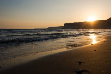 Gün batımı sırasında kumsala yaklaşırken dalgalar