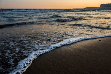 Günbatımı sırasında kumsala yaklaşırken dalgalar