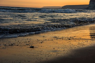 Günbatımı sırasında kumsala yaklaşırken dalgalar