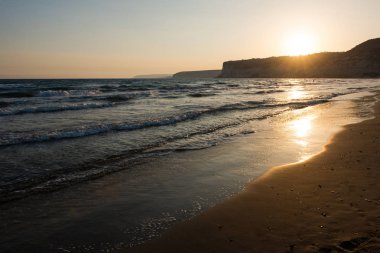 Gün batımı sırasında kumsala yaklaşırken dalgalar