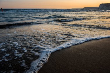 Günbatımı sırasında kumsala yaklaşırken dalgalar